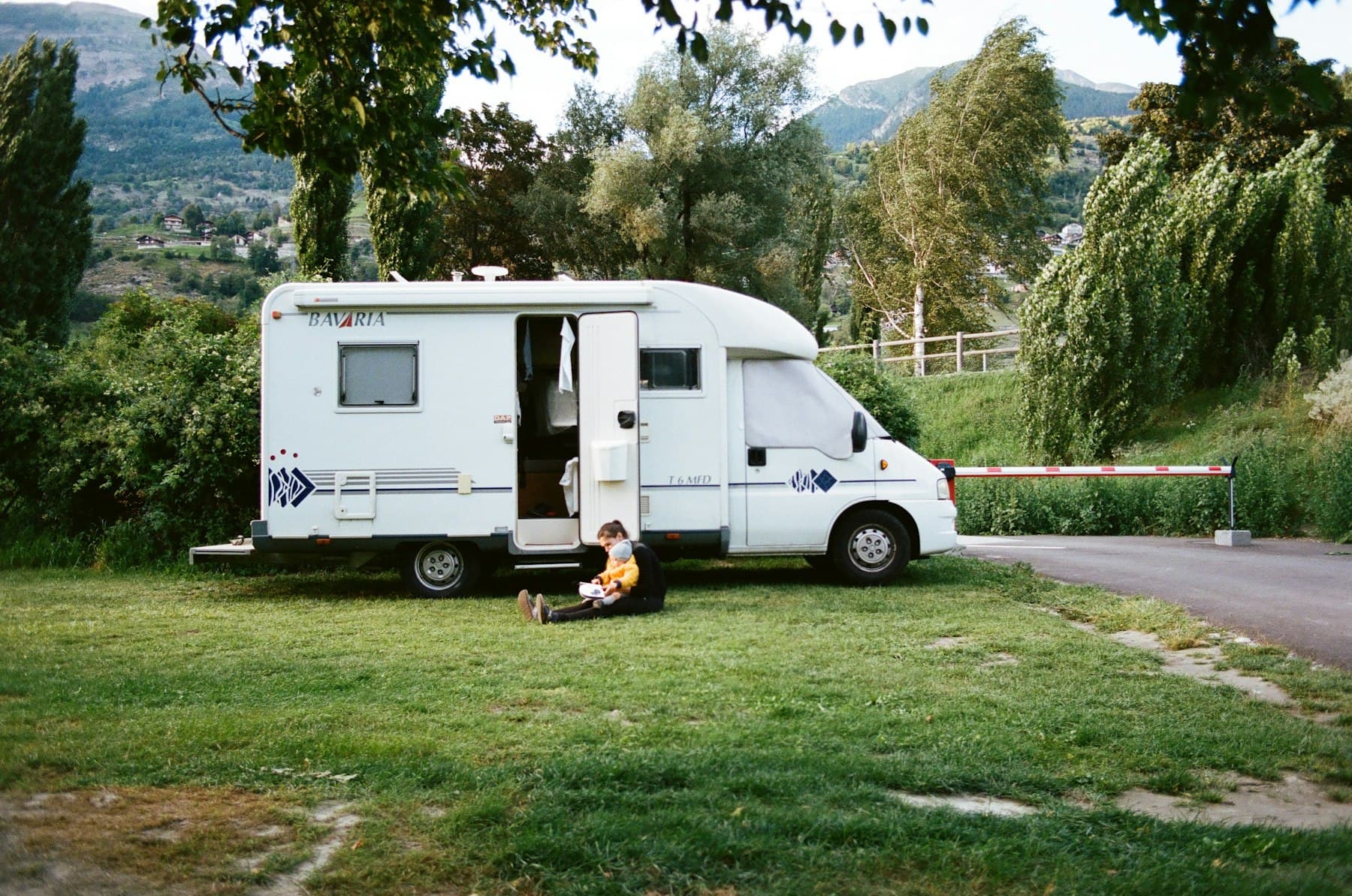 A white RV trailer parked on a grassy meadow at golden hour